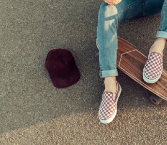 Tanara cu espadrile Vans tinand picioarele pe o placa de skateboard