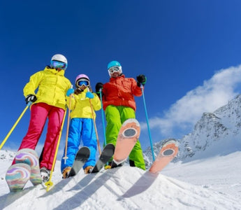 Tineri cu echipamente de ski colorate, pe partie, cu muntele inzapezit pe fundal
